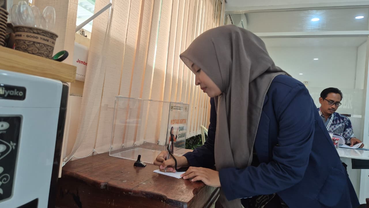 Pengguna layanan menuliskan kritik dan saran untuk dimasukkan ke Kotak Lapor